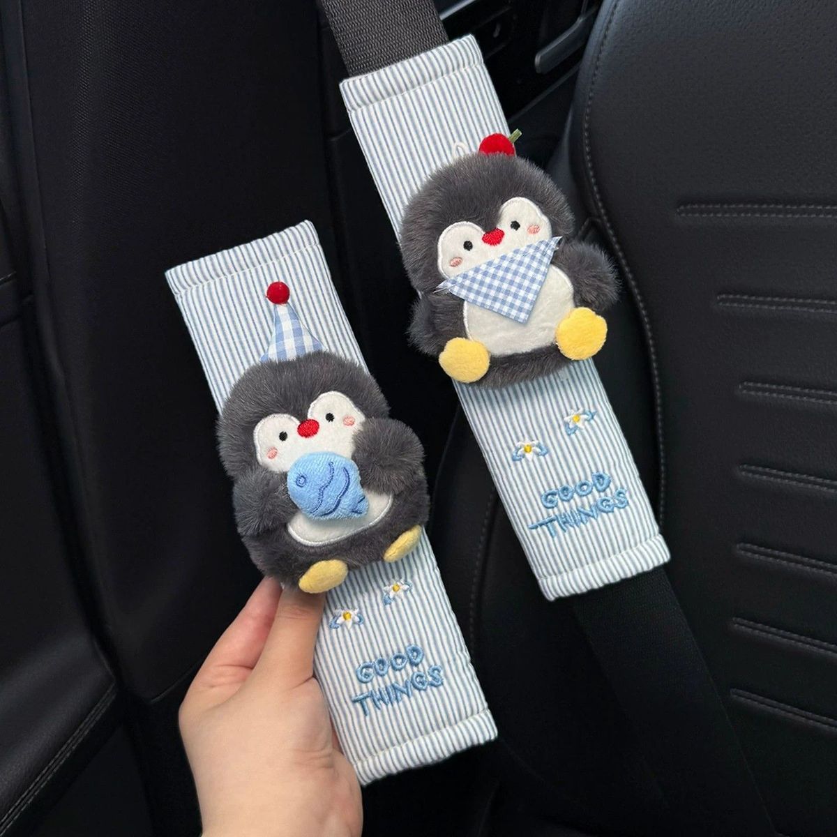 Blue striped seat belt covers with a party penguin and fish penguin.