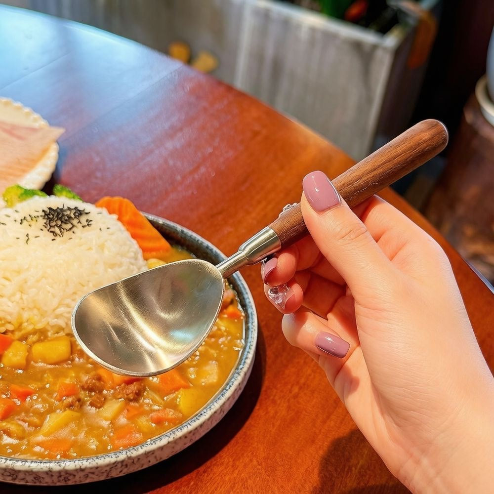 Watermelon baller spoon with a walnut-style handle held over a bowl of fruit for serving.