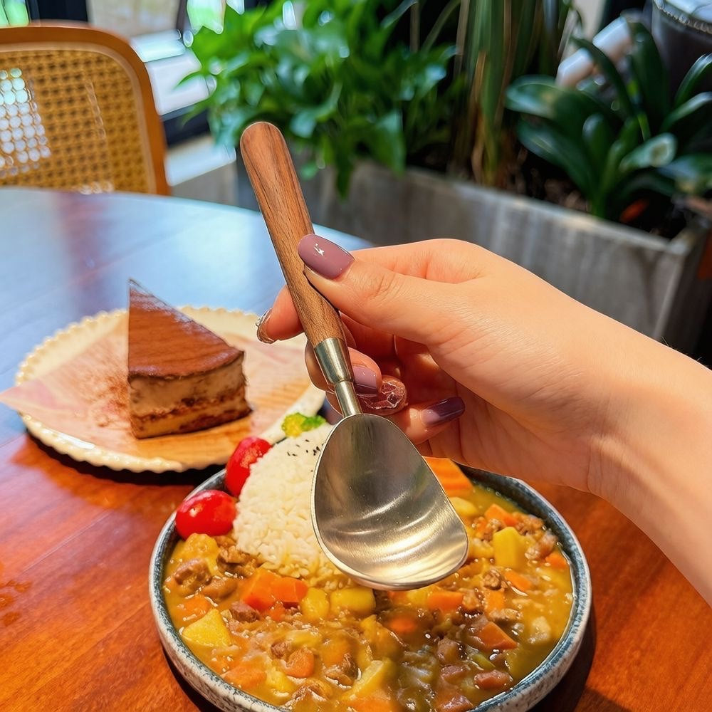 Stainless steel melon baller spoon presented over a prepared fruit bowl for serving.