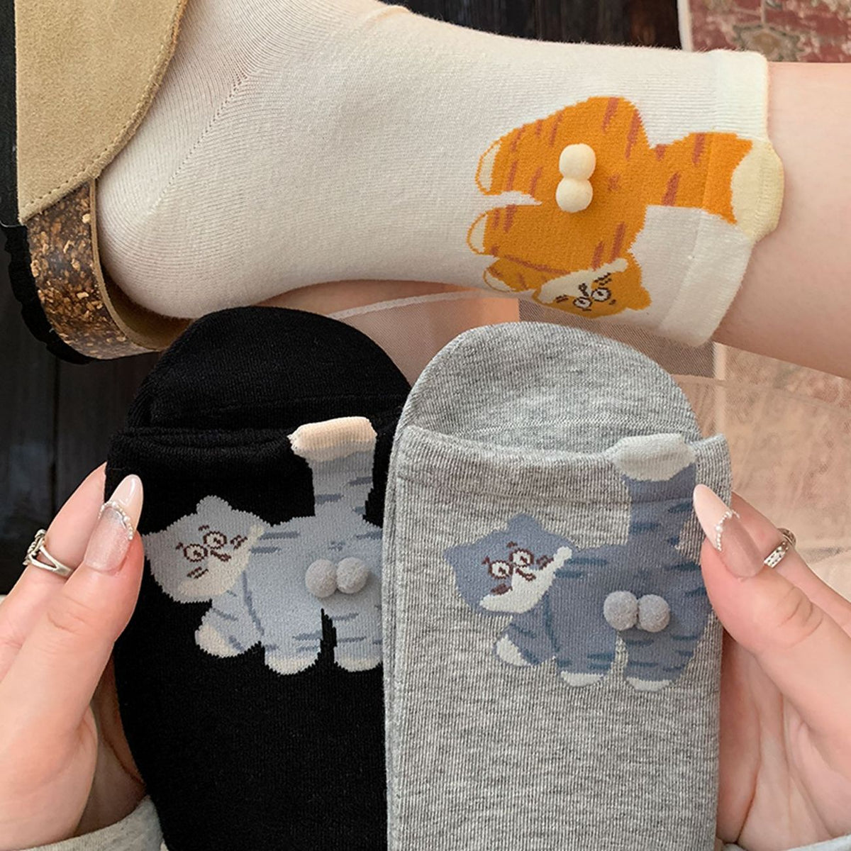 Black and grey cat socks showing raised pom details