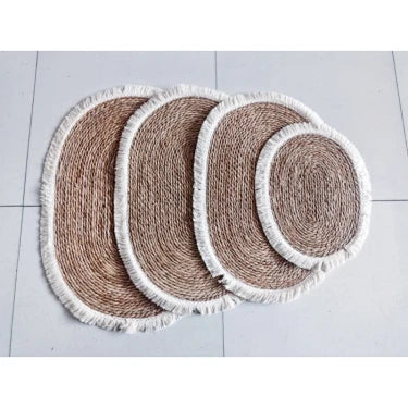 Four oval woven straw mats with light fringe in different sizes