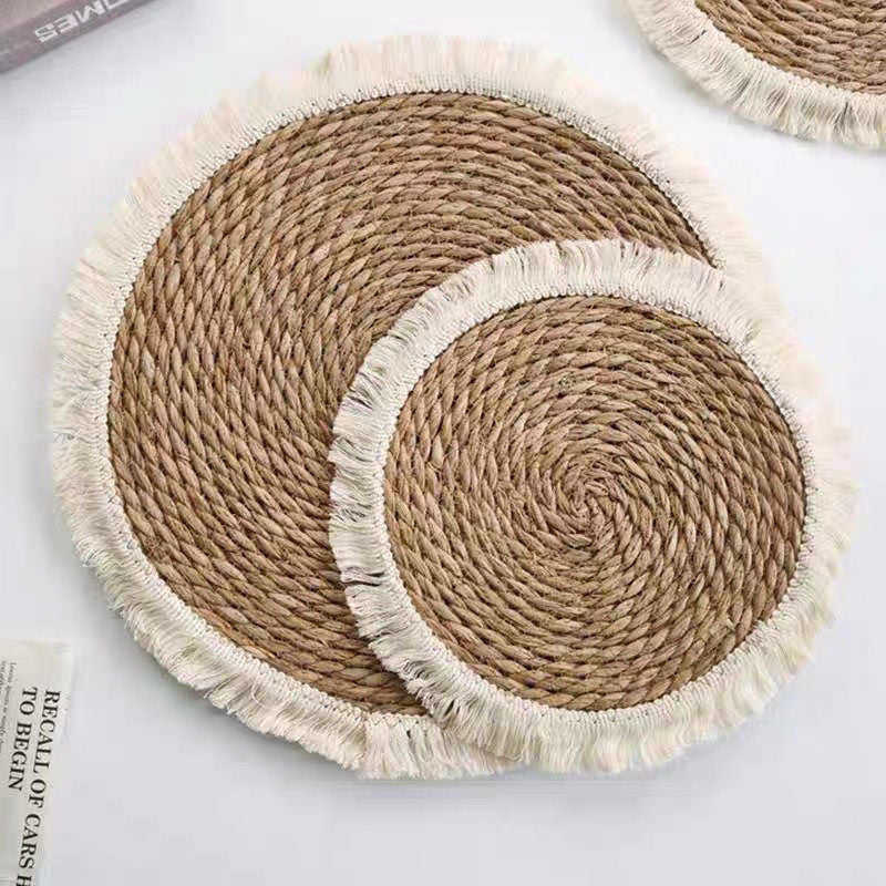 Two round handwoven straw mats with fringed edges