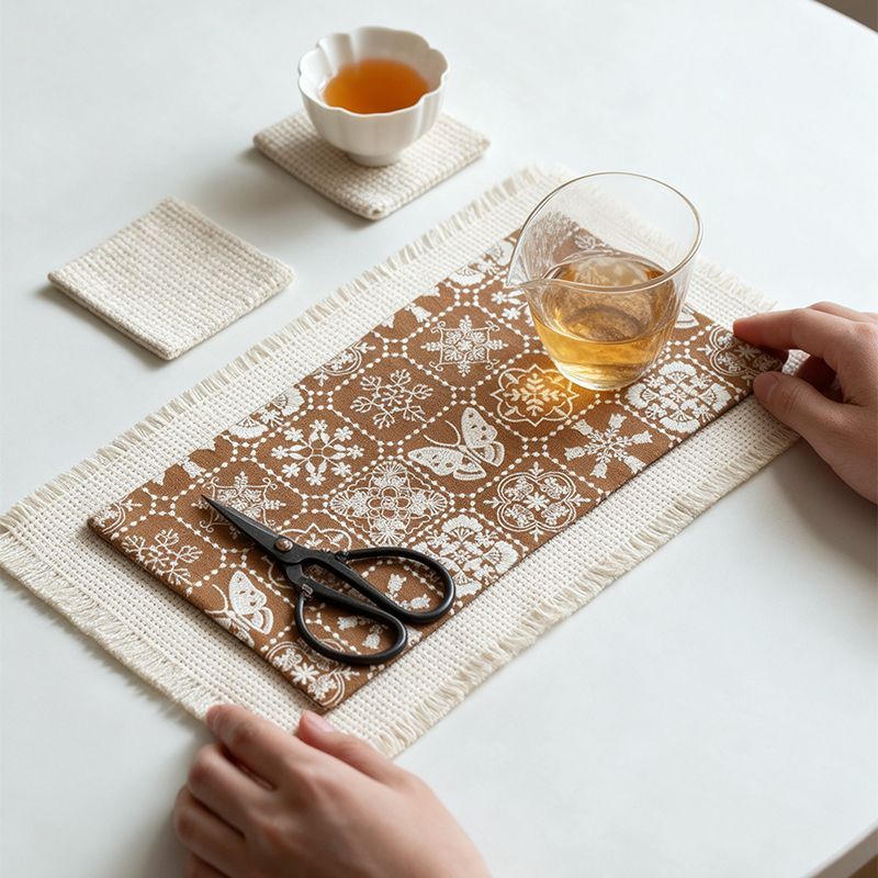Brown patterned cotton-linen tea mat layered over a fringed base mat